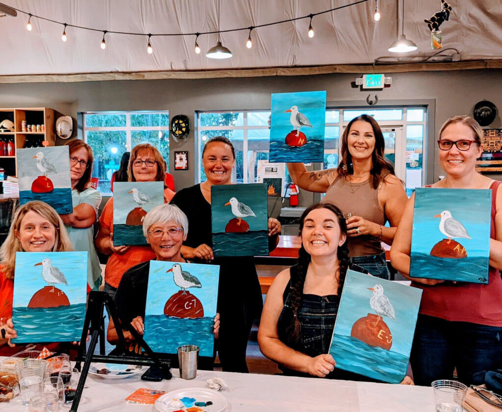 Adults enjoying a creative birthday celebration at a brewery with painting supplies and drinks