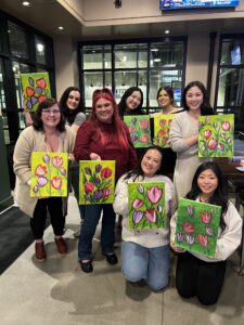 Group of guests holding their unique paintings after a creative birthday celebration