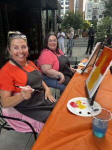 two women smiling and painting at an artvana paint and sip